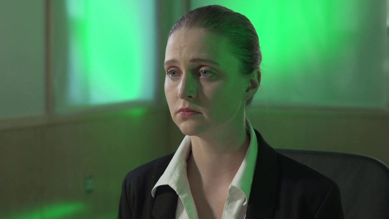 Still from indie short film Cynthetic. Jenna Hill sitting down bathed in green light.